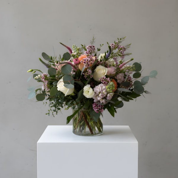 Mixed bouquet of roses and pastel flowers in a glass vase
