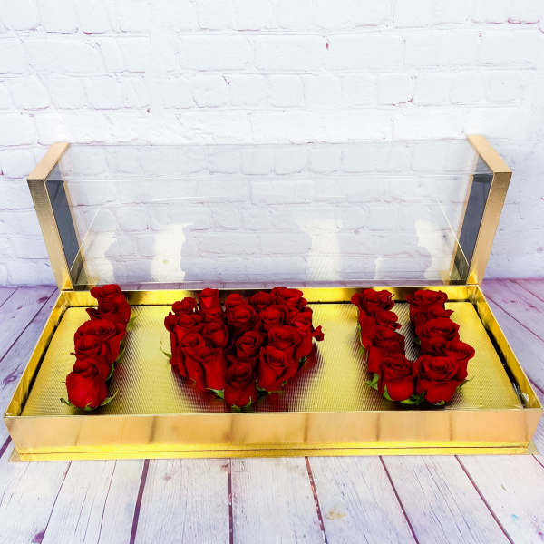 Red roses arranged in a gold box to spell "I U"