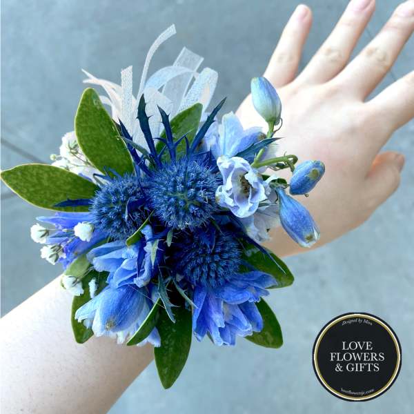 Blue and white wrist corsage worn on a person’s arm