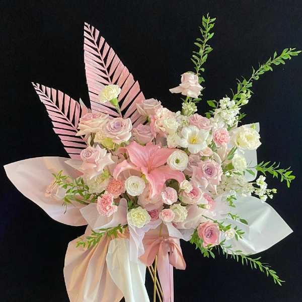 Pink and white floral arrangement with ribbon on tall gold stands