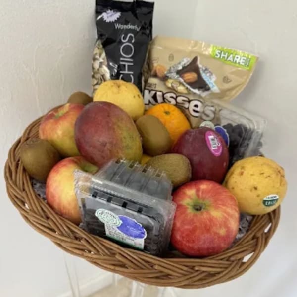 Fruit basket with apples, kiwis, oranges, and packaged snacks
