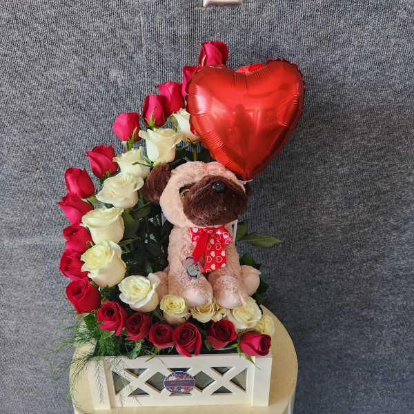 Heart-shaped rose arrangement with a plush dog and red balloon in a white box