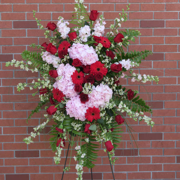 Standing floral spray with red roses, pink hydrangeas, and red gerbera daisies
