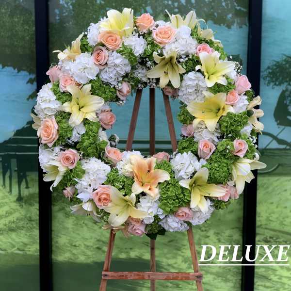 Heart-shaped floral wreath with pink roses, white hydrangeas, and yellow lilies on an easel