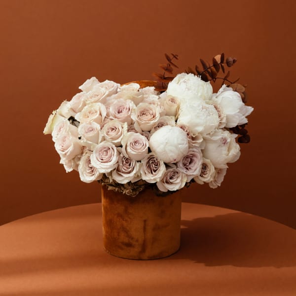 Cream and blush roses with white peonies in a brown vase