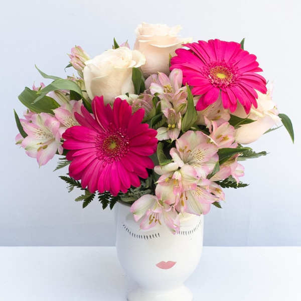 Pink gerbera daisies and pale roses in a white vase
