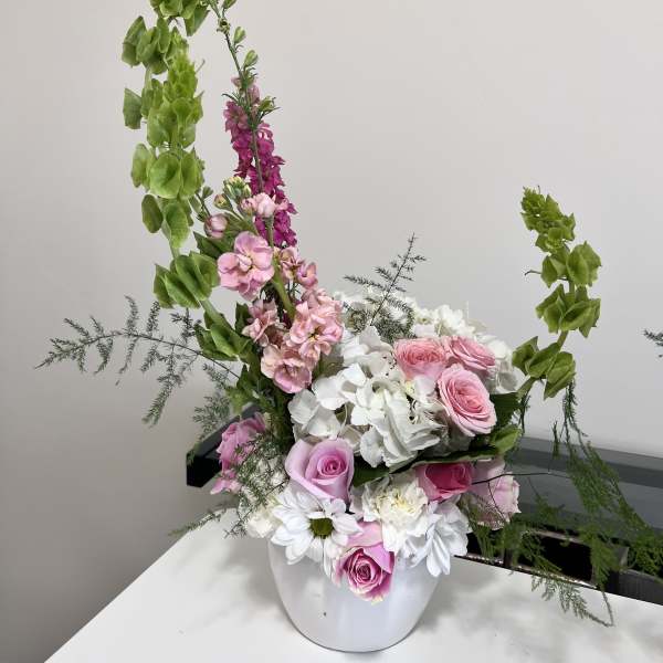 Pink roses and white hydrangeas in a white vase with tall green accents