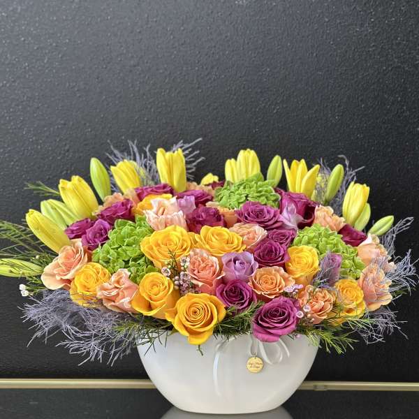 Bright mixed flower arrangement in a white bowl vase