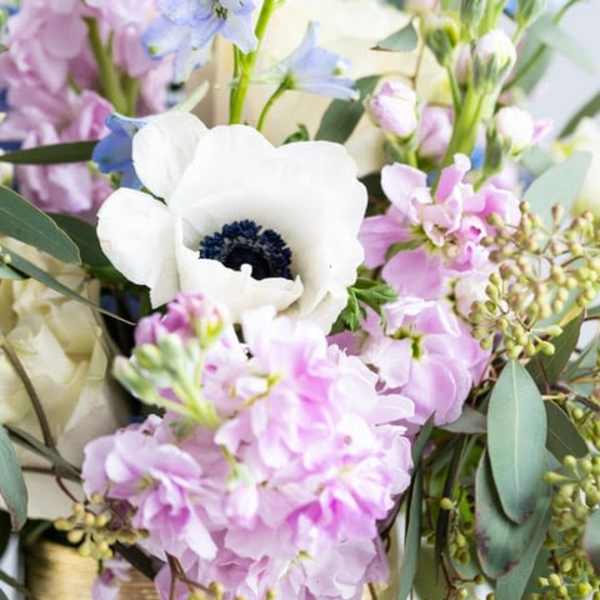 Pastel bouquet with white anemone, pink stock, and light blue delphinium flowers.