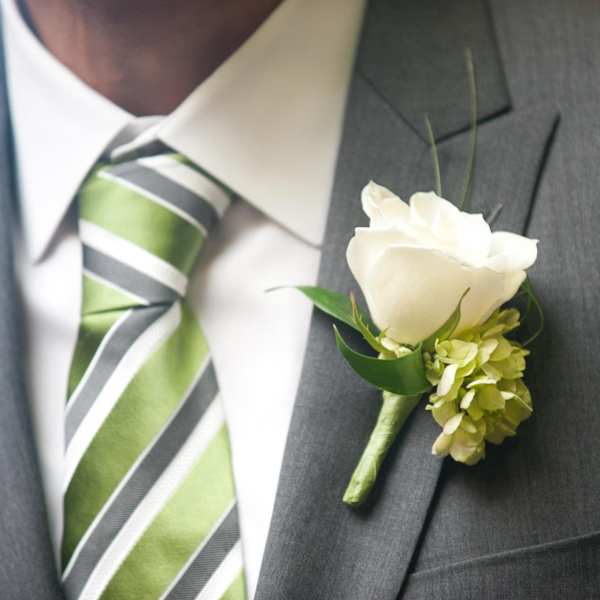 White rose boutonniere pinned to a gray suit jacket