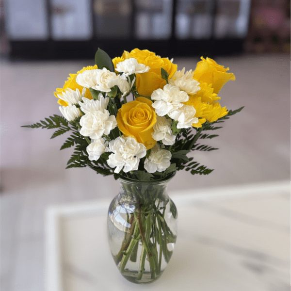 Yellow roses and white carnations in a clear glass vase