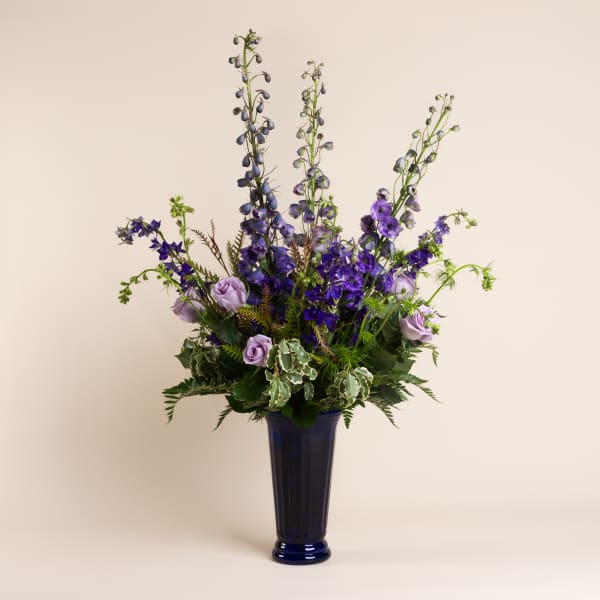 Tall purple floral arrangement in a blue vase