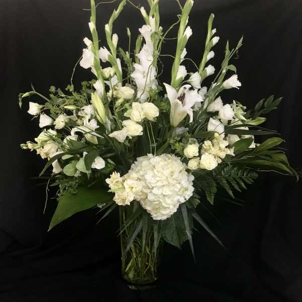 White floral arrangement in a clear glass vase with tall stems and lilies