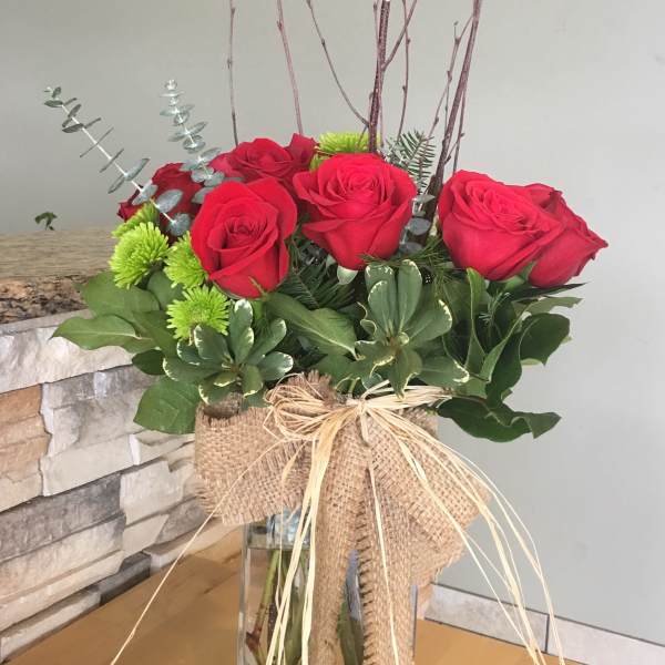 Bouquet of red roses in a glass vase with burlap wrap