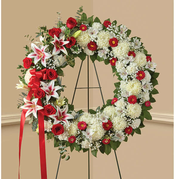 Large floral wreath with red roses and white lilies on a stand