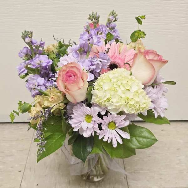 Pastel bouquet in a glass vase with roses, hydrangea, and daisies