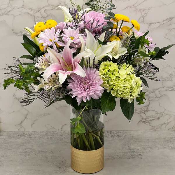 Mixed bouquet of lilies, chrysanthemums, and hydrangea in a glass vase