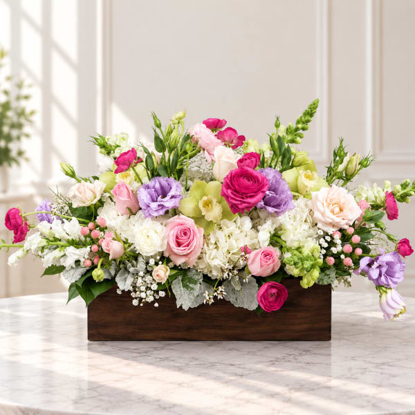 Mixed pink, purple, and white flowers arranged in a wooden box