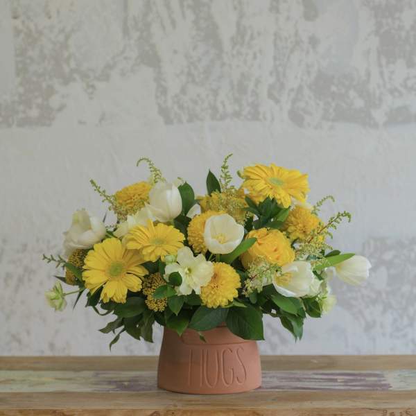 Yellow and white flower arrangement in a terracotta vase