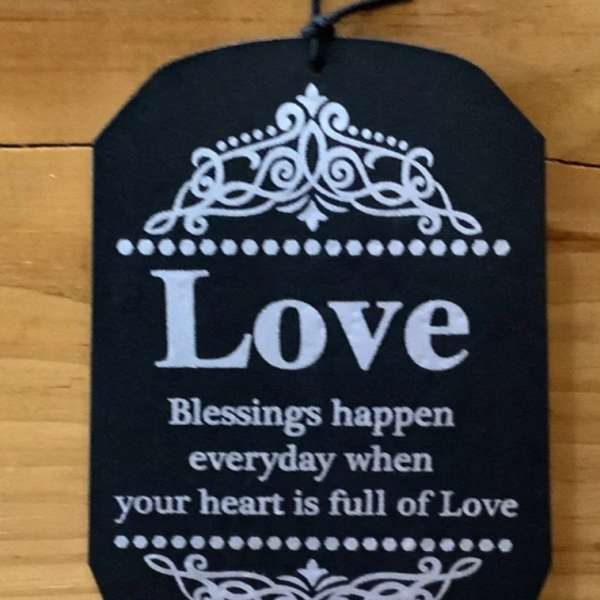 Black hanging plaque with the word Love and decorative white scrollwork