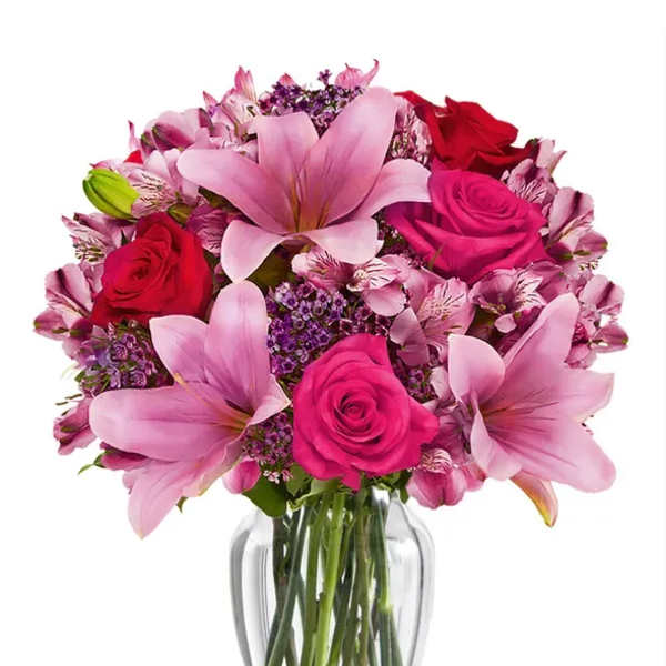 Pink lilies and roses arranged in a clear glass vase