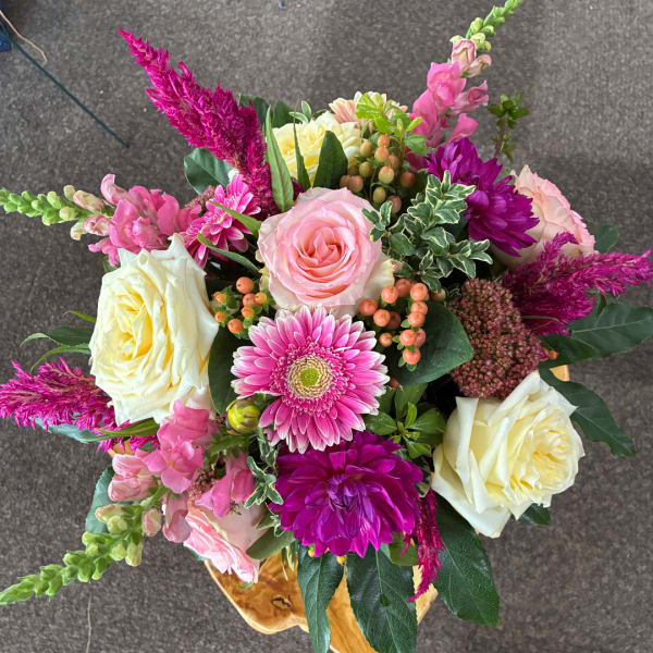 Mixed bouquet of pink and cream roses with bright magenta blooms in a vase
