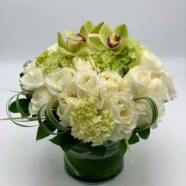 White roses and green orchids in a glass vase
