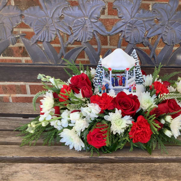 Red roses and white flowers arranged around a small holiday gazebo centerpiece