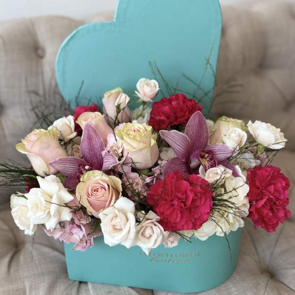 Mixed bouquet of pink and white roses, orchids, and carnations in a turquoise box