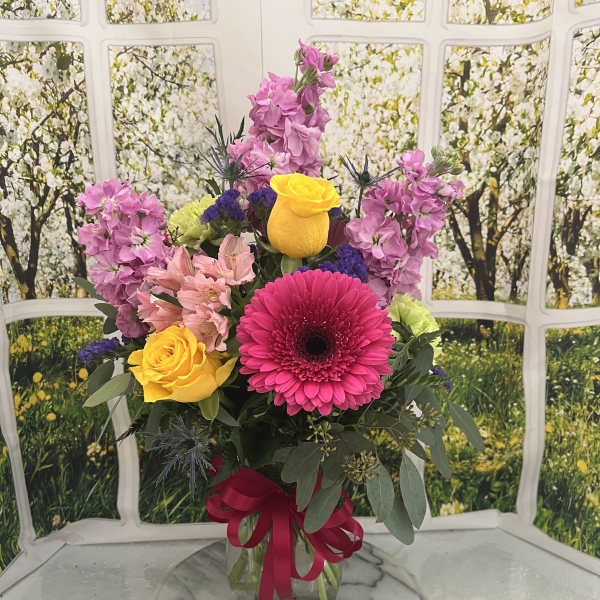 Mixed bouquet in a glass vase with pink, yellow, and purple flowers