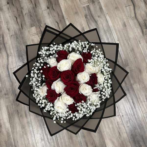 Round bouquet of red and white roses with baby's breath in black wrap