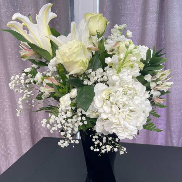 White lilies and hydrangeas in a black vase