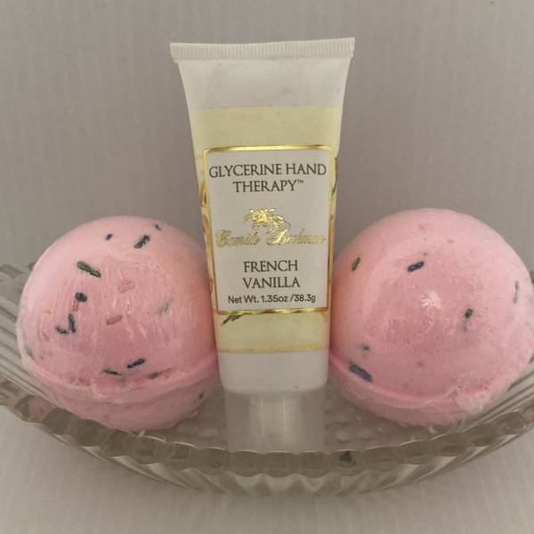 Hand therapy tube in a glass dish with two pink bath bombs