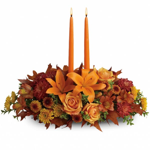 Orange floral centerpiece with two taper candles