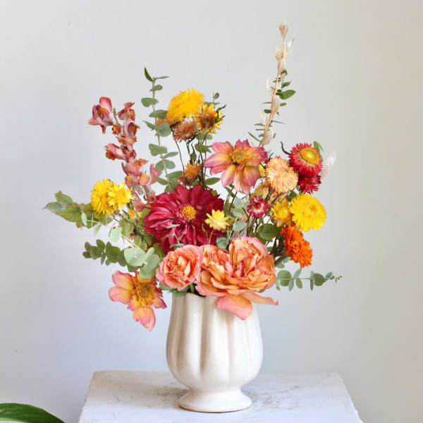 Mixed bouquet in a white vase with pink, yellow, and orange flowers