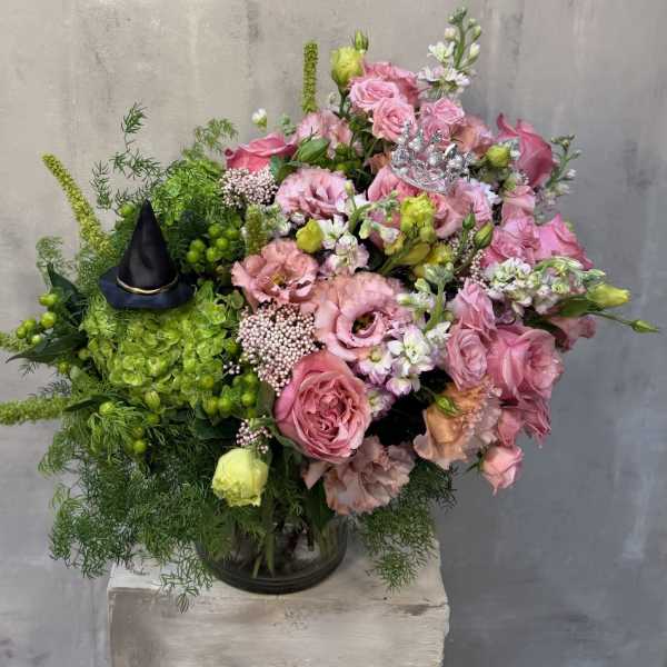 Pink rose bouquet with green accents and a small black witch hat
