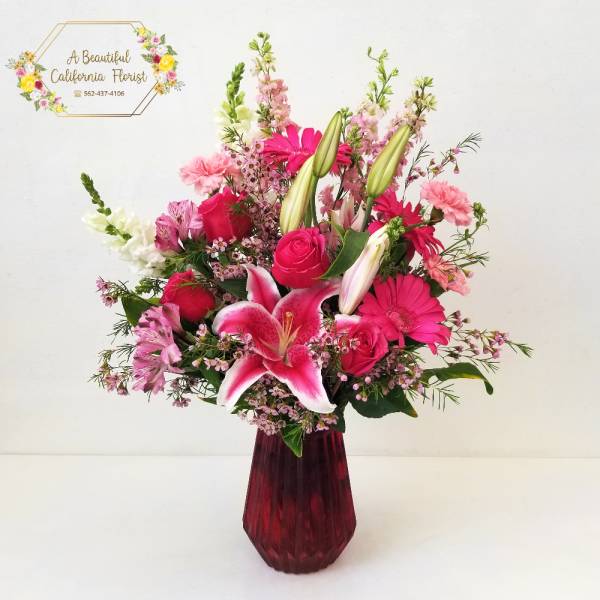 Pink and white mixed bouquet in a red glass vase