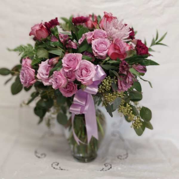 Pink rose bouquet in a glass vase with a lavender ribbon