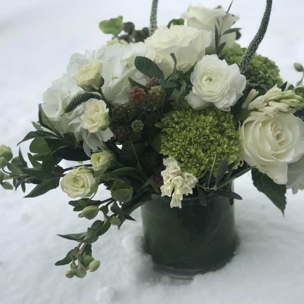 White and green floral arrangement in a dark vase