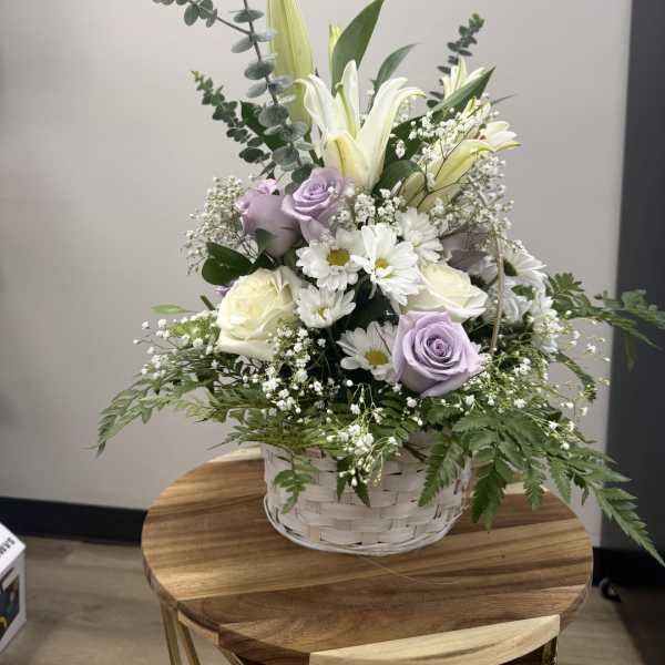Basket arrangement with white lilies, lavender roses, and white daisies