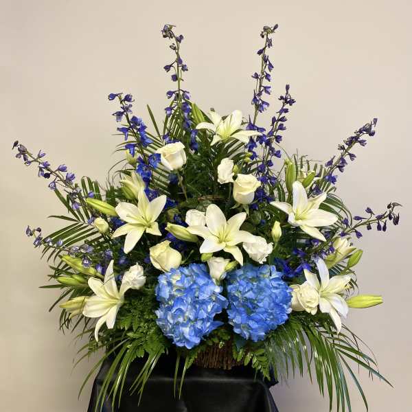 Large floral arrangement with white lilies, blue hydrangeas, and purple flowers