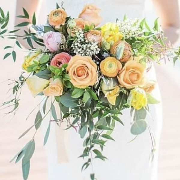 Bouquet of peach, pink, and yellow flowers with trailing greenery
