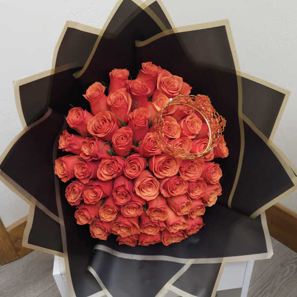 Bouquet of orange roses wrapped in black paper with gold trim