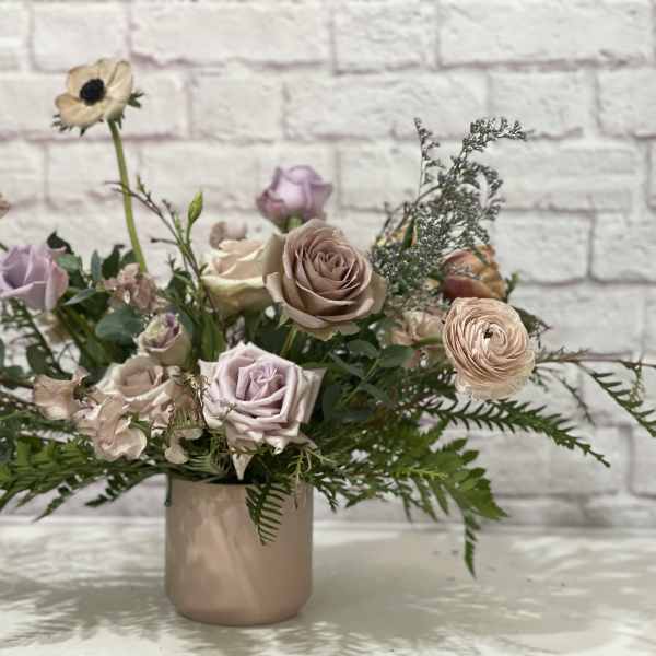 Pastel bouquet of roses and ranunculus in a blush ceramic vase