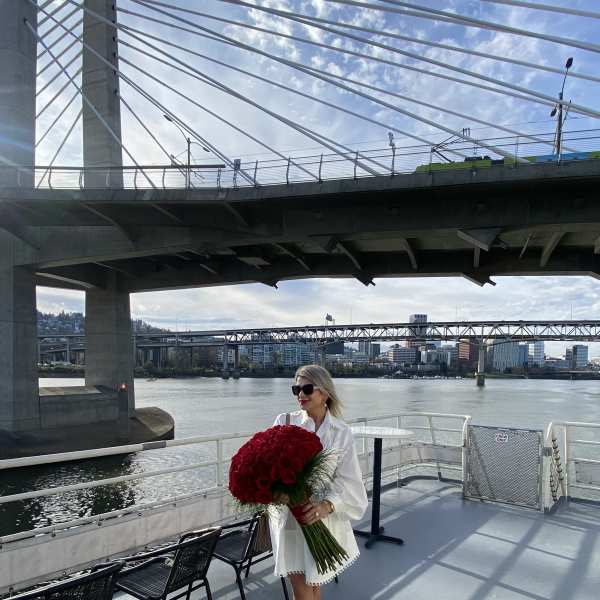 Woman holding a large bouquet of red flowers on a boat deck