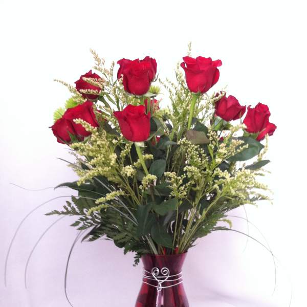 Red roses arranged in a burgundy glass vase