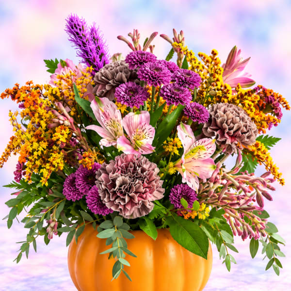 Mixed bouquet in a pumpkin-shaped container with pink, purple, and yellow flowers