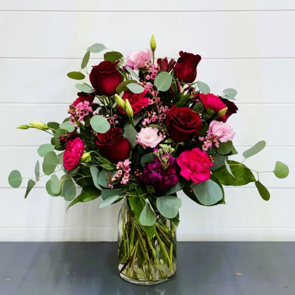 Bouquet of red roses and pink flowers in a clear glass vase