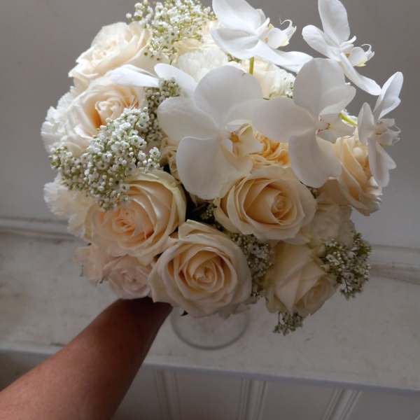 Bouquet of cream roses and white orchids in a clear vase