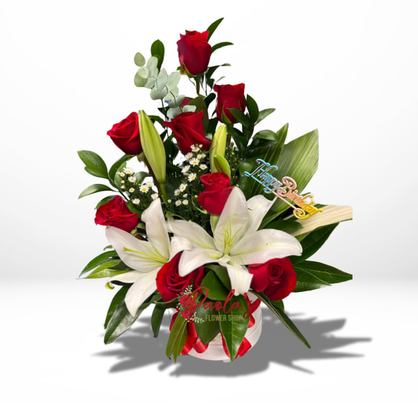 Red roses and white lilies in a white vase with a birthday pick